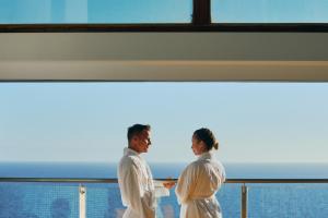 two people standing on a balcony looking at the ocean at Gloria Palace Amadores Thalasso & Hotel in Puerto Rico de Gran Canaria