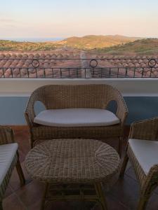 una sedia e uno sgabello in vimini seduti su un balcone di Residenza Il Melograno a Budoni