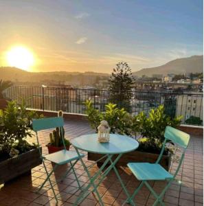 einen Tisch und zwei Stühle auf einem Balkon mit Blick auf den Sonnenuntergang in der Unterkunft Attico Oltremare B&B in Neapel