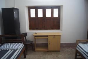 Habitación con escritorio, ventana y mesa. en Cornerbunker en Mysore