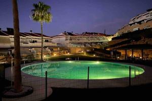 uma piscina à noite com uma palmeira e edifícios em Cozy Loft in Mijas Costa for nature and sea lovers em Mijas Costa