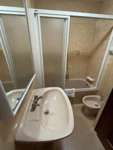 a bathroom with a sink and a tub and a toilet at Hostal Restaurante Luz de Luna in Villanueva de Arosa