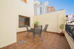 Un patio con sillas y una mesa en el balcón. en EnjoyGranada Corrala Atico Veleta en Granada