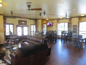 a living room with leather furniture and a restaurant at Hotel Texas Cuero in Cuero