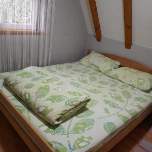 Holiday home Milenkovic في Vrnjačka Banja: سرير لحاف أخضر وبيض ونافذة
