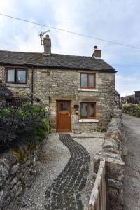 a stone house with a brick path leading to it at Chatterbox Cottage in Wirksworth