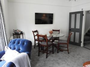 Purlins Holiday Apartment في ساليزبري: غرفة معيشة مع طاولة وكراسي وتلفزيون