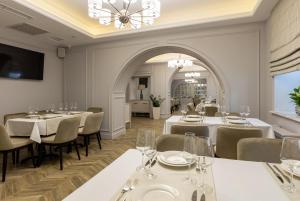 ein Restaurant mit weißen Tischen und Stühlen und einem Kronleuchter in der Unterkunft Dvoryansky Hotel in Odessa