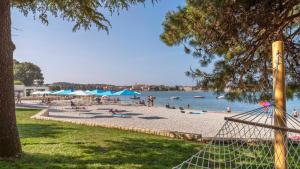 people on a beach with blue umbrellas and the water at Studio Central - 50 meters from Sea in Poreč