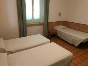 a room with two beds and a window at Hotel Amico Fritz in Livorno