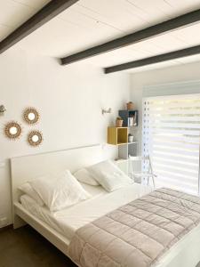 una camera da letto con un grande letto bianco e una finestra di Chambre indépendante avec terrasse privée et piscine a Nîmes