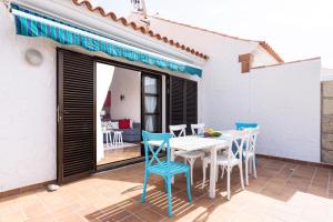 a patio with a white table and blue chairs at Casa Limon - Ocean View - BBQ - Garden - Terrace - Free Wifi - Child & Pet-Friendly - 2 bedrooms - 6 people in Poris de Abona