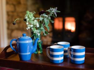 three blue and white cups and a vase with flowers at Lily Cottage in Great Tew