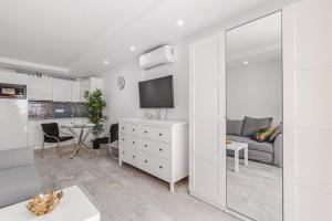 a white living room with a couch and a tv at Tenerife Royal Gardens One Bedroom Apartment in Playa de las Americas