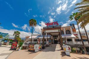a street with palm trees in front of a store at Tenerife Royal Gardens One Bedroom Apartment in Playa de las Americas
