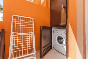 a washing machine in a room with an orange wall at Tenerife Royal Gardens One Bedroom Apartment in Playa de las Americas