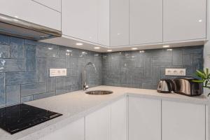 a kitchen with white cabinets and a sink at Tenerife Royal Gardens One Bedroom Apartment in Playa de las Americas