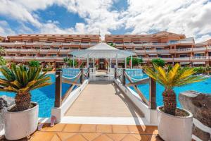 a resort with a boardwalk leading to a swimming pool at Tenerife Royal Gardens One Bedroom Apartment in Playa de las Americas