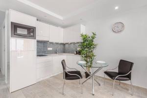 a kitchen with a table and chairs and a clock at Tenerife Royal Gardens One Bedroom Apartment in Playa de las Americas