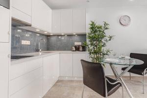 a kitchen with white cabinets and a table with a plant at Tenerife Royal Gardens One Bedroom Apartment in Playa de las Americas