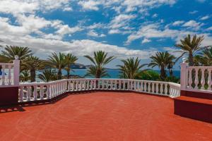 a balcony with a white railing and palm trees at Tenerife Royal Gardens One Bedroom Apartment in Playa de las Americas