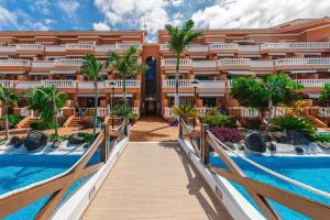 a resort with a wooden walkway leading to a pool at Tenerife Royal Gardens One Bedroom Apartment in Playa de las Americas