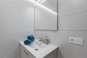 a white bathroom with a sink and a mirror at Tenerife Royal Gardens One Bedroom Apartment in Playa de las Americas