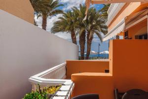 a balcony of a building with palm trees and the beach at Tenerife Royal Gardens One Bedroom Apartment in Playa de las Americas