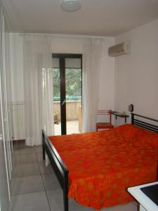 a bedroom with a red bed and a balcony at Appartamento Sirolo in Sirolo