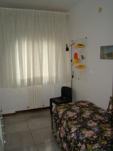 ein Schlafzimmer mit einem Bett, einem Stuhl und einem Fenster in der Unterkunft Appartamento Sirolo in Sirolo