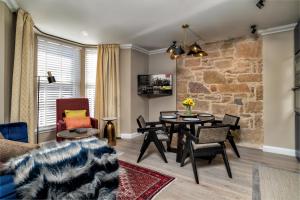 a living room with a stone wall and a table and chairs at Pamper yourself in our DOUBLE SIZED copper tub -2 bedroom villa in Inverness