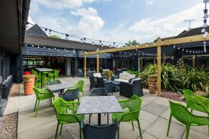 an outdoor patio with green chairs and tables and chairs at Holiday Inn Cambridge by IHG in Cambridge