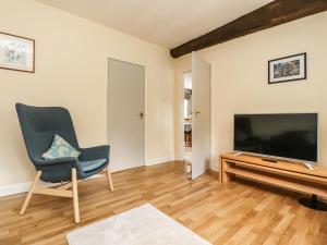 a living room with a flat screen tv and a chair at Grange House in Skipton