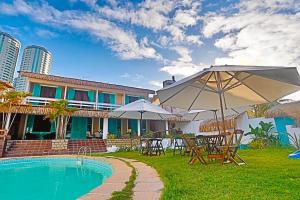 a pool with tables and umbrellas next to a house at Pousada Ponta Mar in Natal