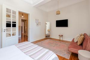 a bedroom with a bed and a couch and a tv at The Local Guest House Lisbon in Lisbon