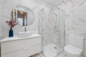 bagno bianco con lavandino e specchio di The Local Guest House Lisbon a Lisbona