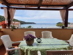 a table with white chairs and a table with flowers on it at Bougenville in Kampor