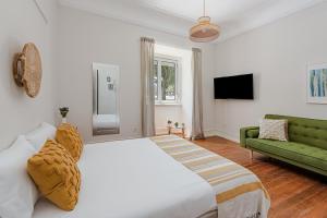 una camera con un grande letto bianco e un divano verde di The Local Guest House Lisbon a Lisbona