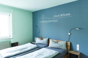 a bedroom with two beds and a blue wall at Hotel Check-Rhein - Self Check-in in Neuenburg am Rhein