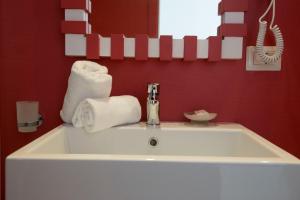 a white sink in a red bathroom with towels at Sorrento ResArt Suite in Sorrento