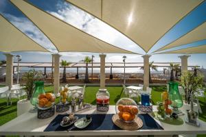 einen Tisch mit Teller mit Lebensmitteln auf einem Tisch mit einem Regenschirm in der Unterkunft Hotel & Spa Entremares in La Manga del Mar Menor