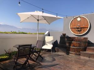 une terrasse avec une table, des chaises et un parasol dans l'établissement Bakenhof Winelands Lodge, à Paarl