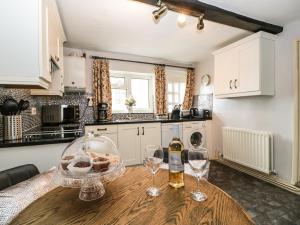 a kitchen with a wooden table with two wine glasses at Cariad Cottage in Ludlow