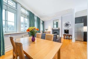 a kitchen and living room with a wooden table with flowers on it at Nelson's Pad - Trafalgar Square - by Frankie Says in London