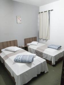 a room with two beds and a window at Hotel Queluz in Conselheiro Lafaiete