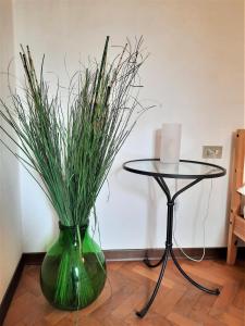 a green vase with grass in it next to a table at Palazzo Calocci appartamenti in Assisi in Assisi