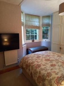 a bedroom with a bed and a flat screen tv at Osborne Lodge in Ryde