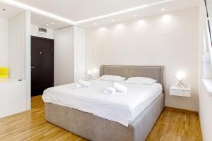 una camera da letto con un grande letto con lenzuola bianche di White Apartments a Belgrado