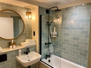 a bathroom with a sink and a shower and a mirror at Greyhound Hotel in Sutton