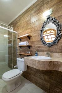 a bathroom with a toilet and a sink and a mirror at Pousada Sons do Silêncio in Socorro